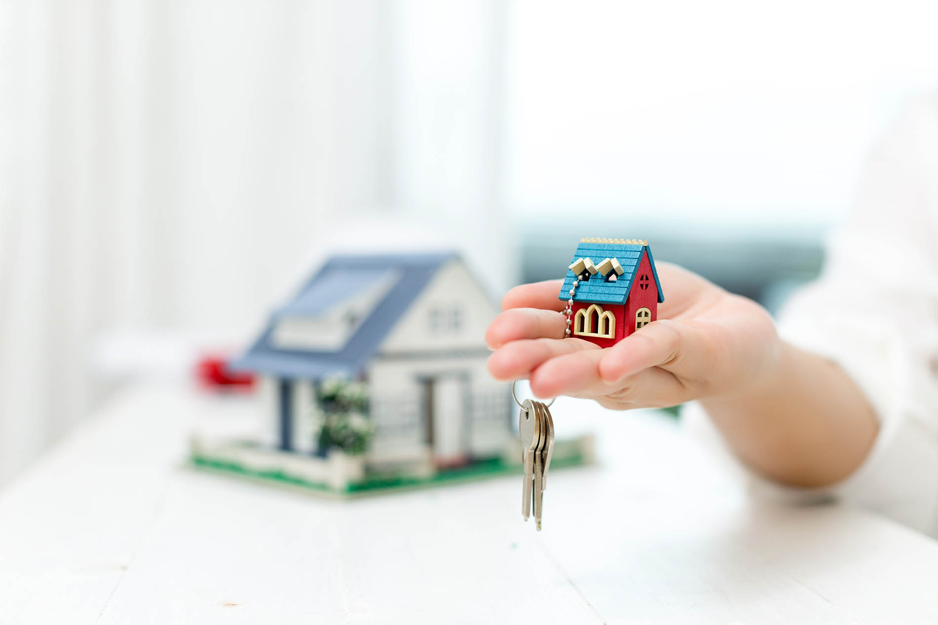 Hand holding a model house and keys